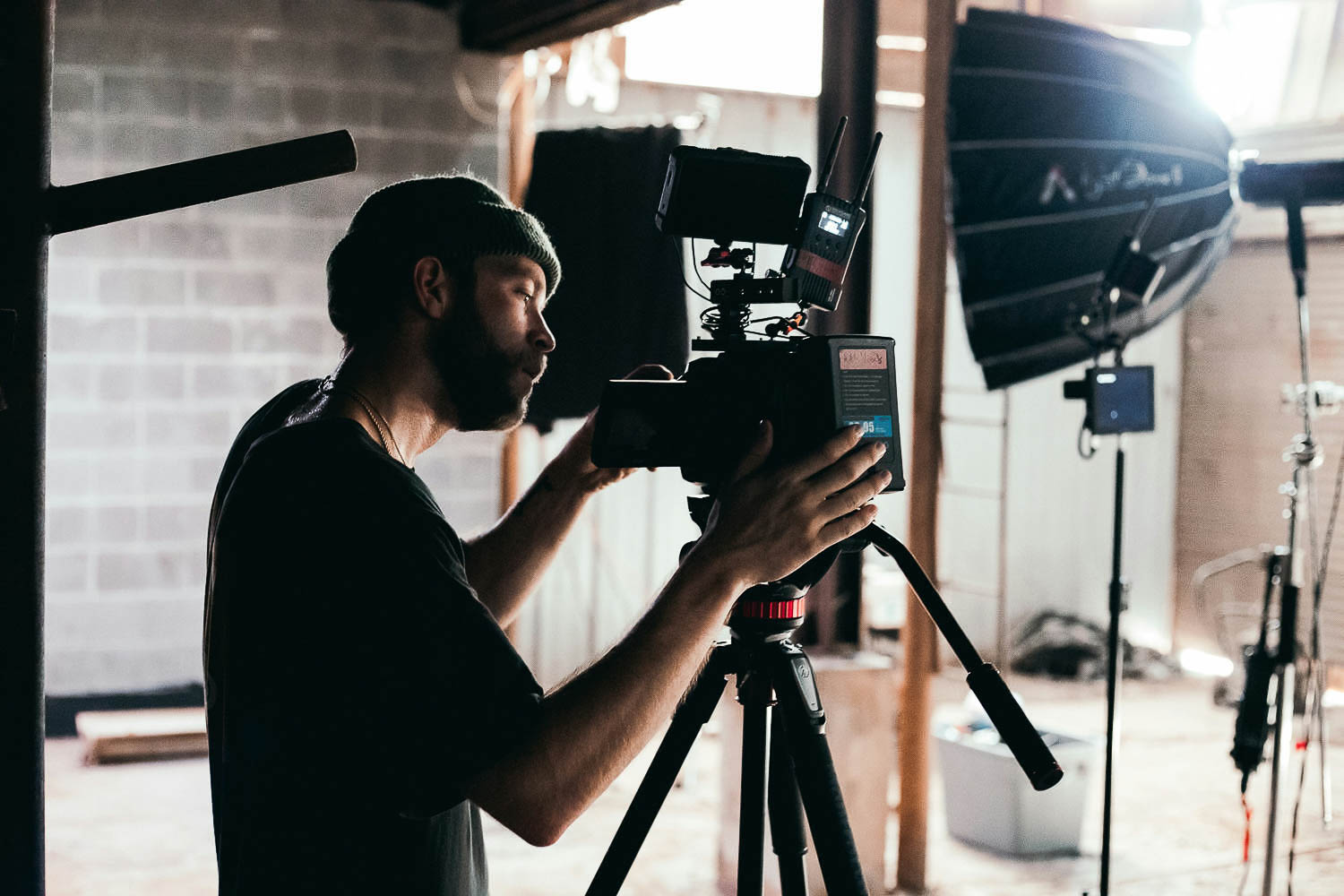Ein Mann bedient eine Videokamera. Im Hintergrund sind verschiedene Geräte für Videoproduktionen zu sehen.